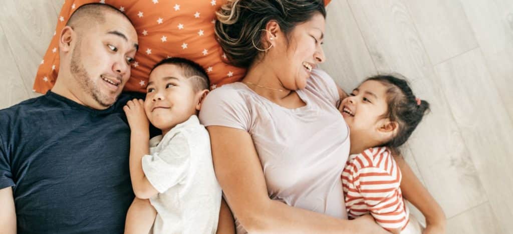 Family laying on the floor laughing and enjoying each other work-life balance NORM